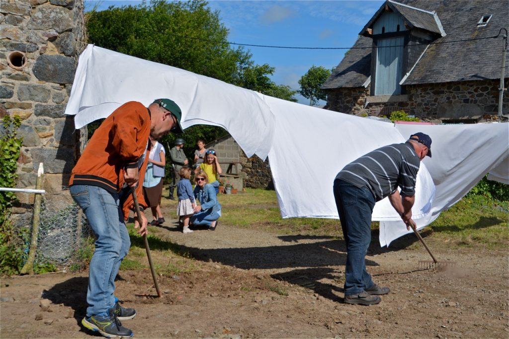 Préparation du décor avec l'installation du fil à linge, des draps et le ratissage du sol.